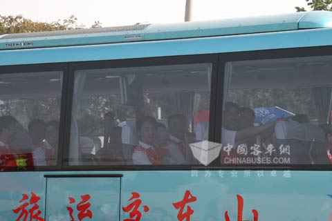 Torch bearers are waving to spectators in Yutong bus
