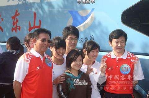 Torch bearers are taking group photos in front of a Yutong bus